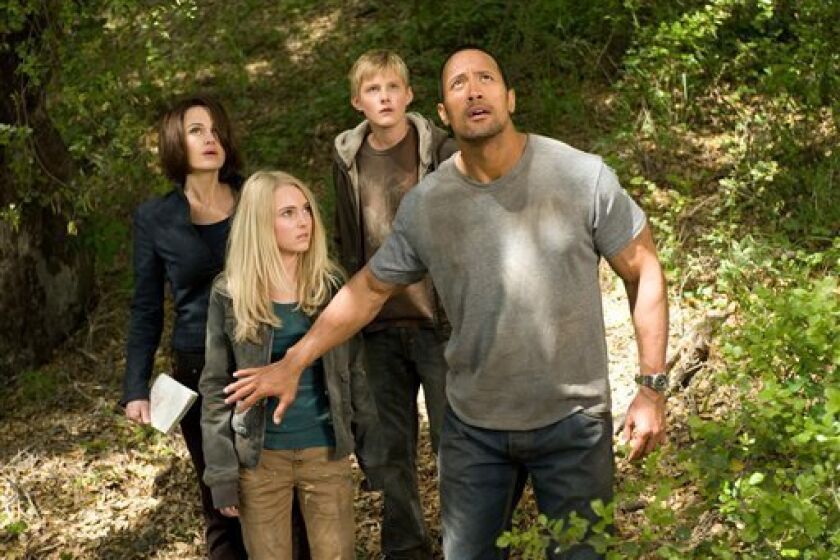 In this film still released by Disney, actors, from left, Carla Gugino, AnnaSophia Robb, Alexander Ludwig and Dwayne Johnson are shown in a scene from "Race to Witch Mountain." The Walt Disney Co. said Tuesday, May 5, 2009, its second-quarter net income fell 46 percent, with sharply lower profits at its movie studio and theme parks. (AP Photo/Disney, Ron Phillips)