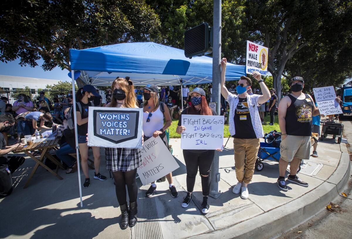 People hold signs including, "Women's voices matter."