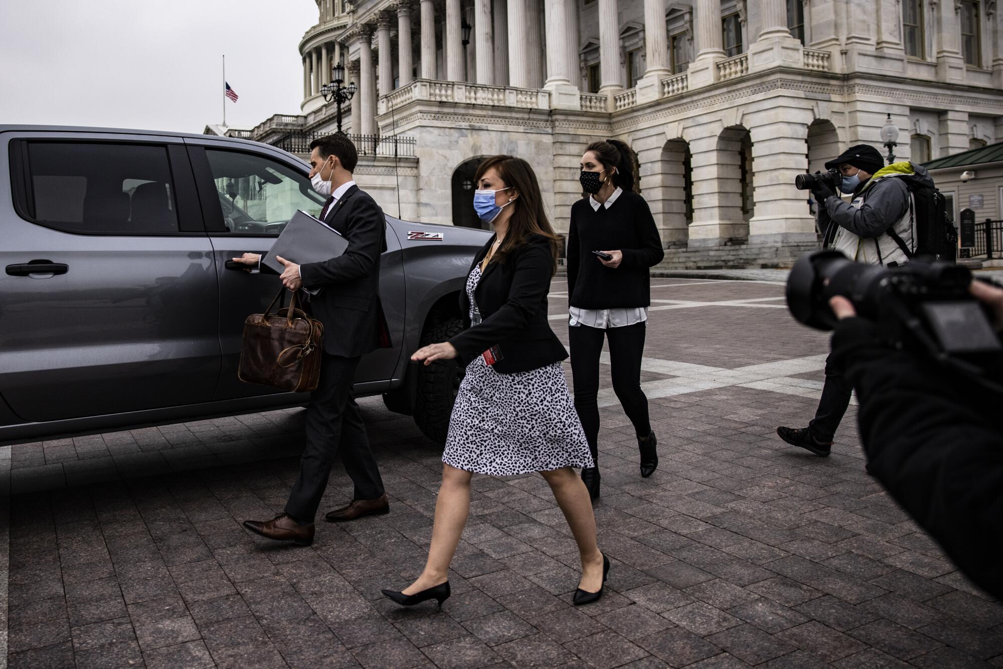 A senator opens the door to an SUV outside the Capitol