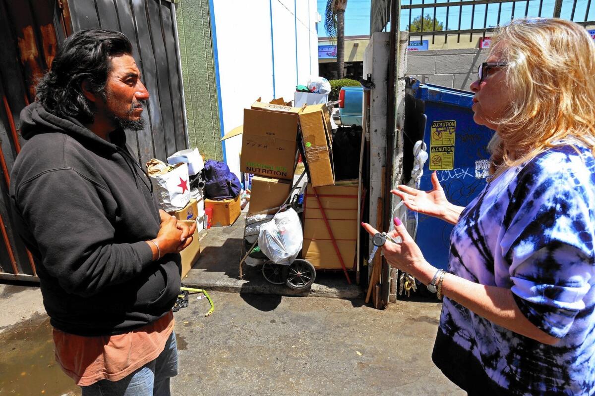 Florist shop owner Bonnie Bernard, right, talks with Angel, a homeless man who has been living with his wife across the way from Bernard's store in a Sylmar shopping center.