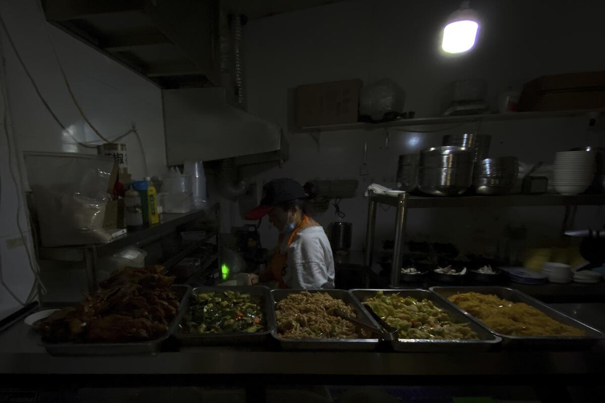 A woman prepares food at a restaurant during a blackout.