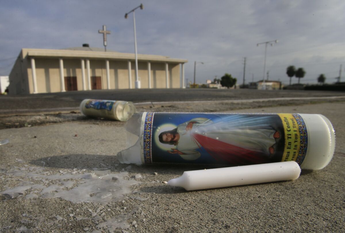 Two prayer candles knocked over by vehicle traffic lie in the driveway of the 88th Street Temple Church of God In Christ in Westmont, where a man walking with his wife was shot to death and a security guard was wounded Wednesday evening.