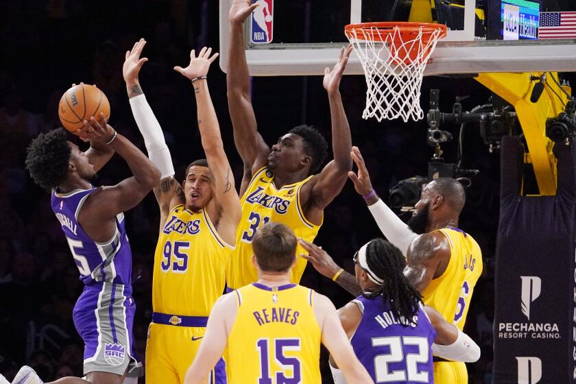 Sacramento Kings guard Davion Mitchell, left, shoots as Los Angeles Lakers forward Juan Toscano-Anderson.