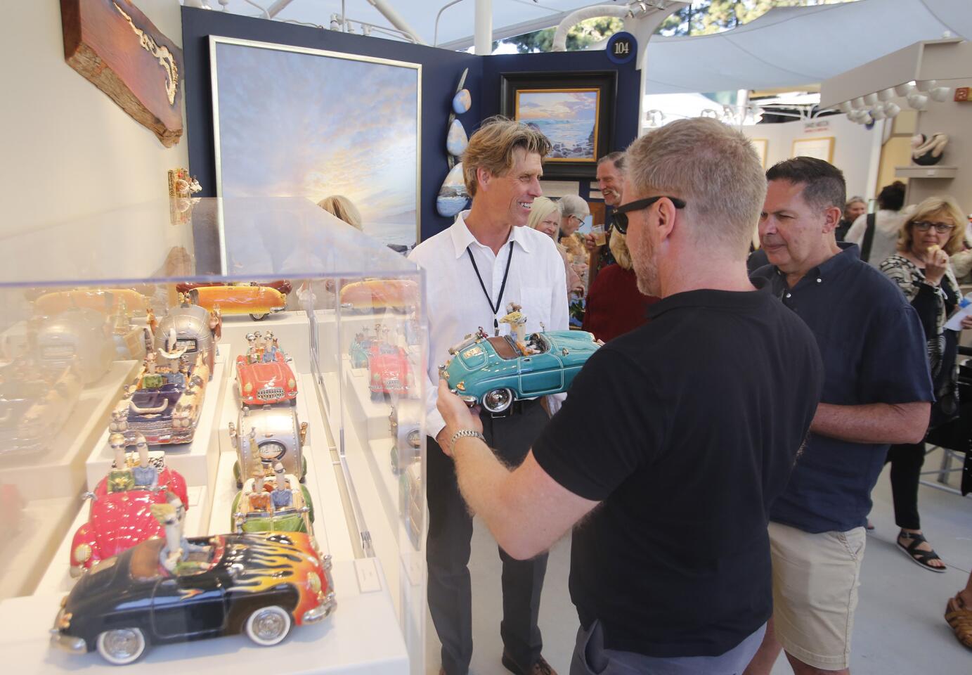 Ceramic artist Scott Schoenherr shares one of his whimsical automotive life pieces with guests during Festival of Arts artist preview party.