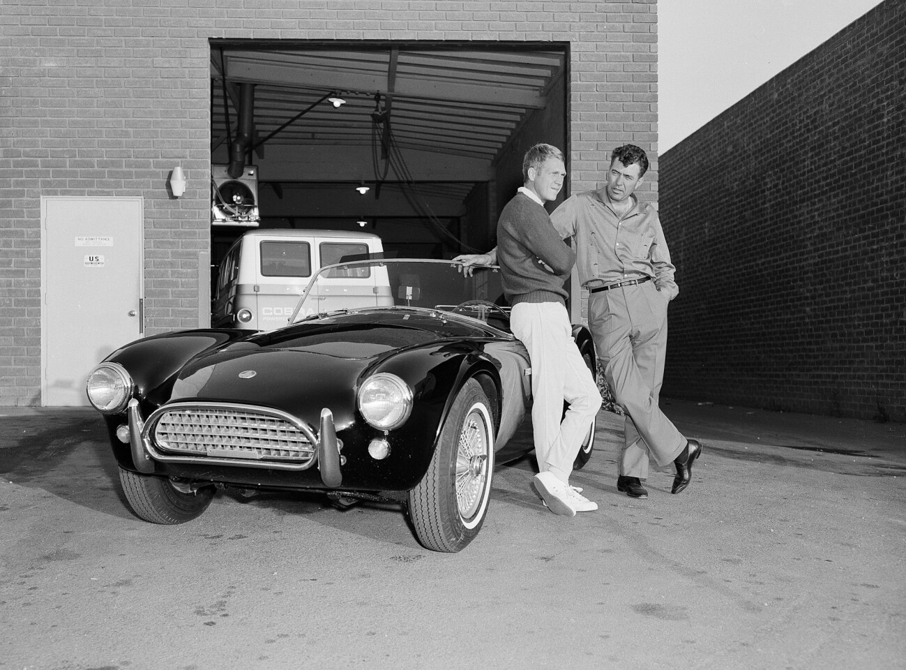 Actor Steve McQueen, left, and racer Carroll Shelby stand by McQueen's Ford Cobra Roadster in 1963.