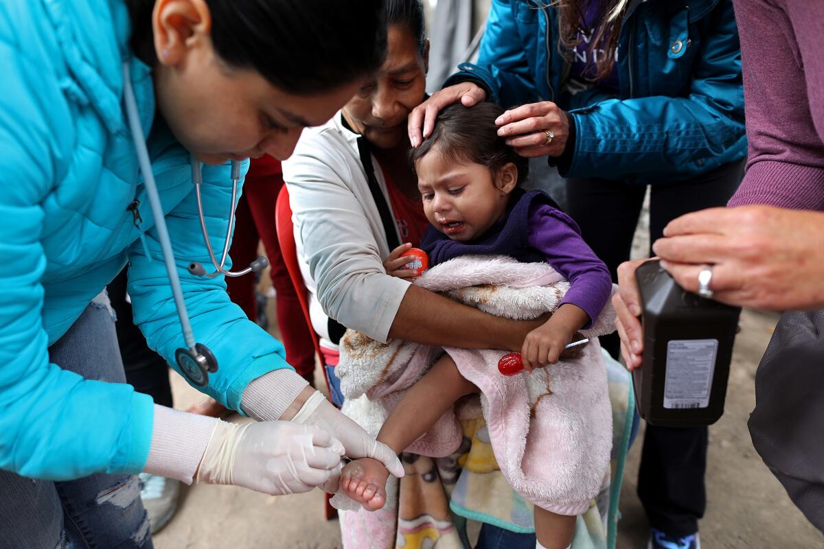 Ofelia Castillo Soto, 46, of Michoacan, Mexico, holds her 1-year-old granddaughter Renata Gonzales Castillo as she receives treatment for burns on both feet near the El Chaparral crossing in Tijuana.
