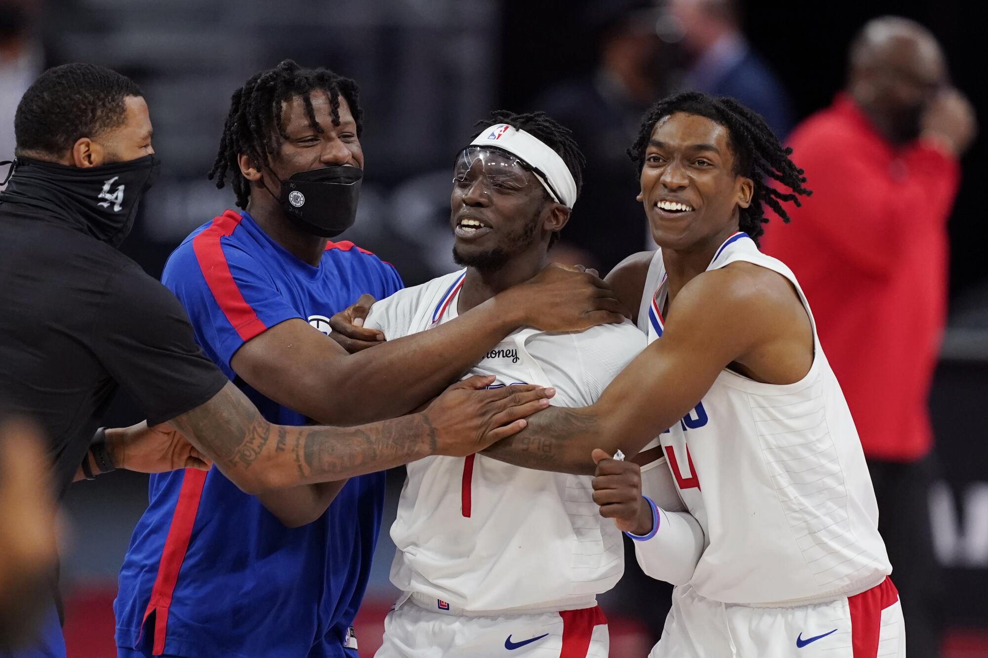 Clippers guard Reggie Jackson is swarmed by teammates after making the game-winning basket against the Pistons.