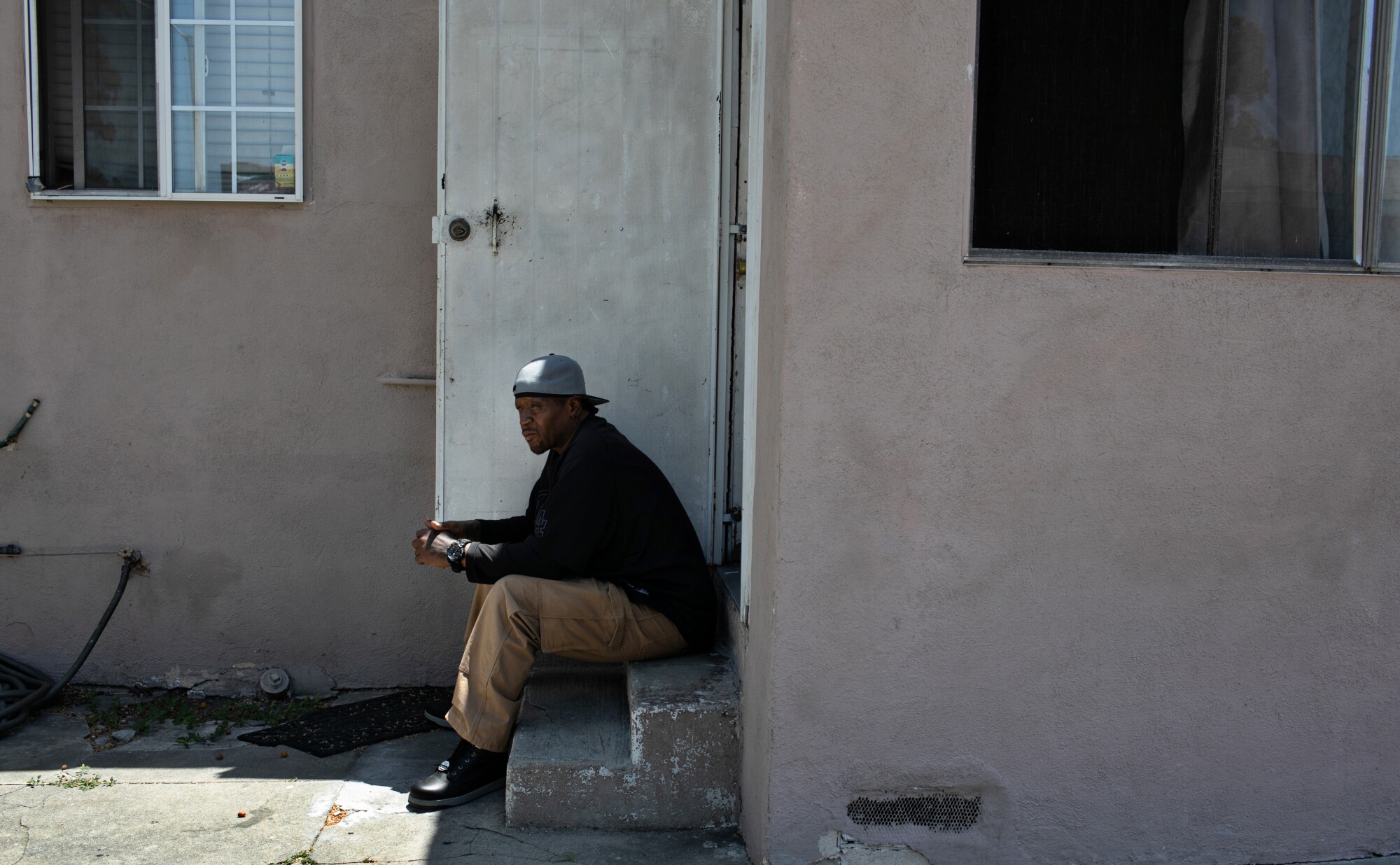 Man sits on step outside house.