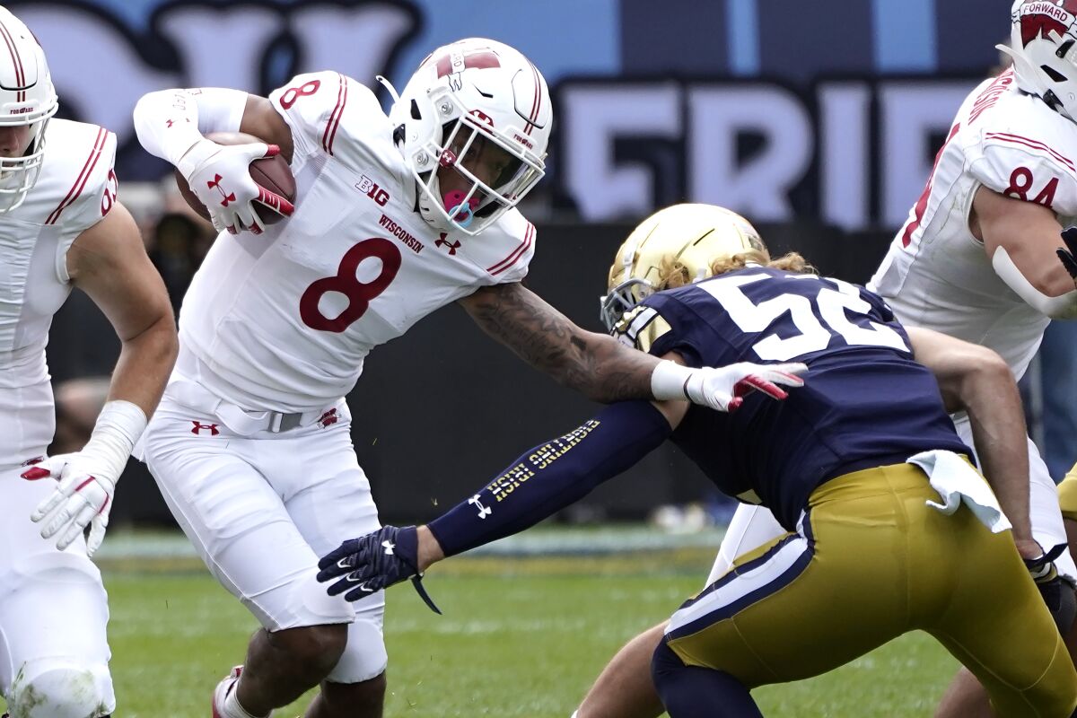 Wisconsin running back Jalen Berger (8) slips past Notre Dame linebacker Bo Bauer during the second half of an NCAA college football game Saturday, Sept. 25, 2021, in Chicago. Notre Dame won 41-13. (AP Photo/Charles Rex Arbogast)