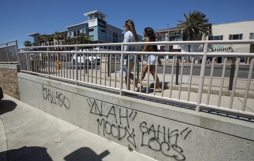 Two women walk on a sidewalk in Huntington Beach. 