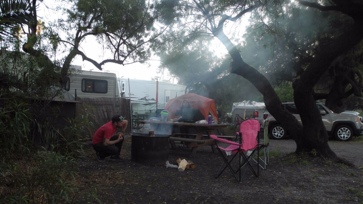 Elyie Florez blows into the fire in Refugio State Beach campsite while writer Denise Florez prepares the stove to sauté vegetables, May 20, 2017. (Nikte Florez)