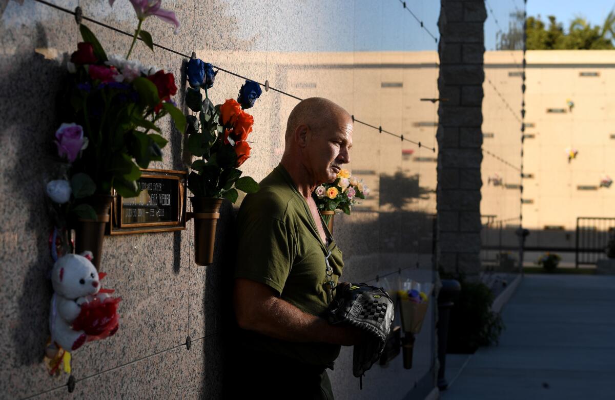 John Weber, holding his son Anthony's glove, stands next to the burial site at Inglewood Cemetery. Sheriff's deputies fatally shot the 16-year-old in South L.A. in February.