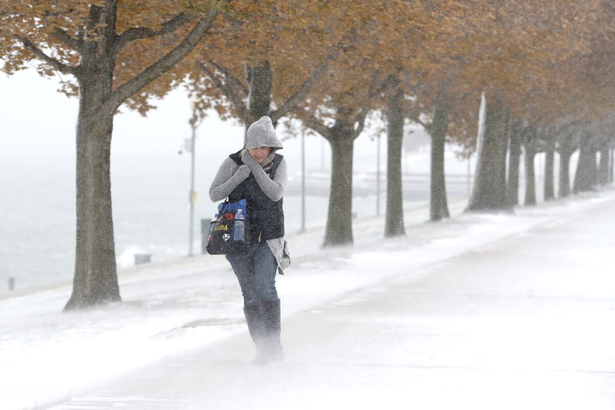 A woman walking the half mile from Chicago's Adler Planetarium to the Chicago Aquarium braces herself in the stiff wind and blowing snow off Lake Michigan Monday, Nov. 11, 2019, in Chicago. (AP Photo/Charles Rex Arbogast)