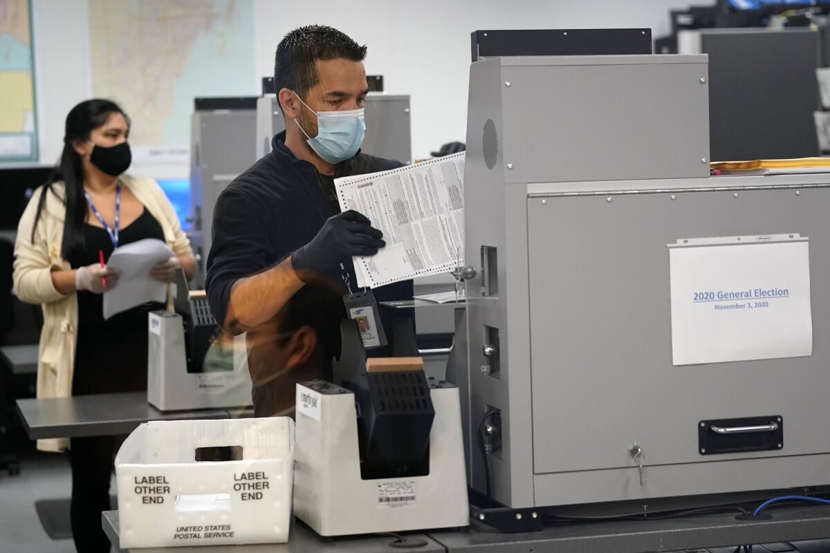 An election worker loads ballots into a scanning machine on Monday in Doral, Fla. 