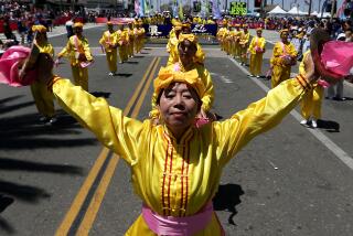 Los Angeles, CA - Members of a group called Falun Dafa perform on Main Street during the Huntington Beach Independence Day Parade on July 4, 2023. Thousands of people gathered in the Orange County coastal community for the annual ecvent. July 04: in Los Angeles on Tuesday, July 4, 2023 in Los Angeles, CA. (Luis Sinco / Los Angeles Times)