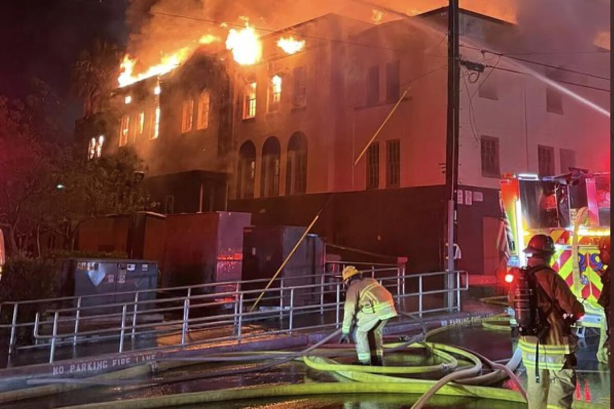 Firefighters battle a blaze at a large building at night.