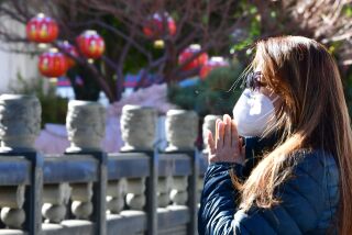 A woman prays on the first day of the Lunar New Year of the Ox outside the Thien Hau Temple, temporarily closed due to the coronavirus pandemic, in the Chinatown neighborhood of Los Angeles, California on February 12, 2021. - Los Angeles is home to one of the largest Asian-American communites in the United States but high Covid-19 infection rates have led to cancelled events and curtailed gatherings. (Photo by Frederic J. BROWN / AFP) (Photo by FREDERIC J. BROWN/AFP via Getty Images)