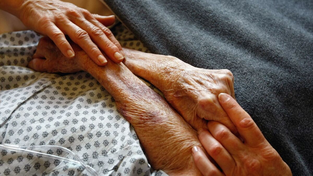 Hospice workers hold the hands of a terminally ill patient in Lakewood, Colo., in 2009.