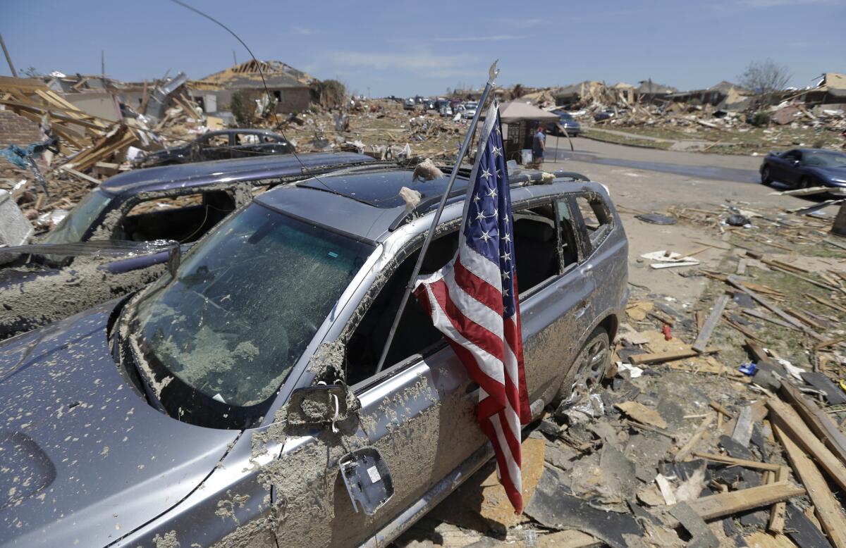 An American flag sits in a destroyed car's window in a neighborhood devastated by the tornado that ripped through Moore, Okla., on Monday