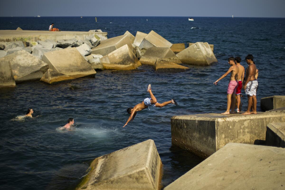 FILE - Youngsters dive into the Mediterranean sea during a hot sunny day in Barcelona, Spain, July 21, 2022. Spain's weather agency said July was Spain's hottest month on record. The agency said Monday, Aug. 8, 2022, that the month had a record-breaking average daily temperature of 25.6 degrees Celsius (78 degrees Fahrenheit). (AP Photo/Francisco Seco, File)