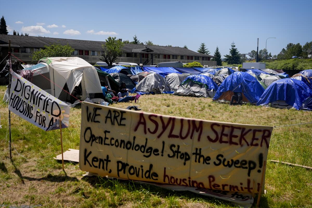 Varios letreros que piden ayuda se encuentran frente a un campamento de solicitantes de asilo 