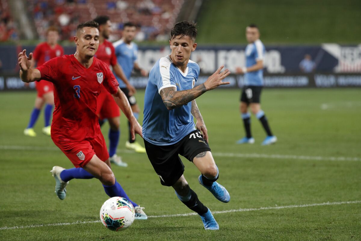 The United States' Aaron Long, left, and Uruguay's Brian Rodriguez chase after a loose ball during a 2019 soccer match.