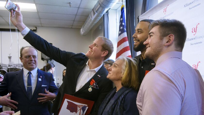 Spencer Stone, left, photographs himself and French Conseillere Consulaire Sophie Lartilleux-Suberville, Anthony Sadler and Alek Skarlatos following a French Naturalization Ceremony.
