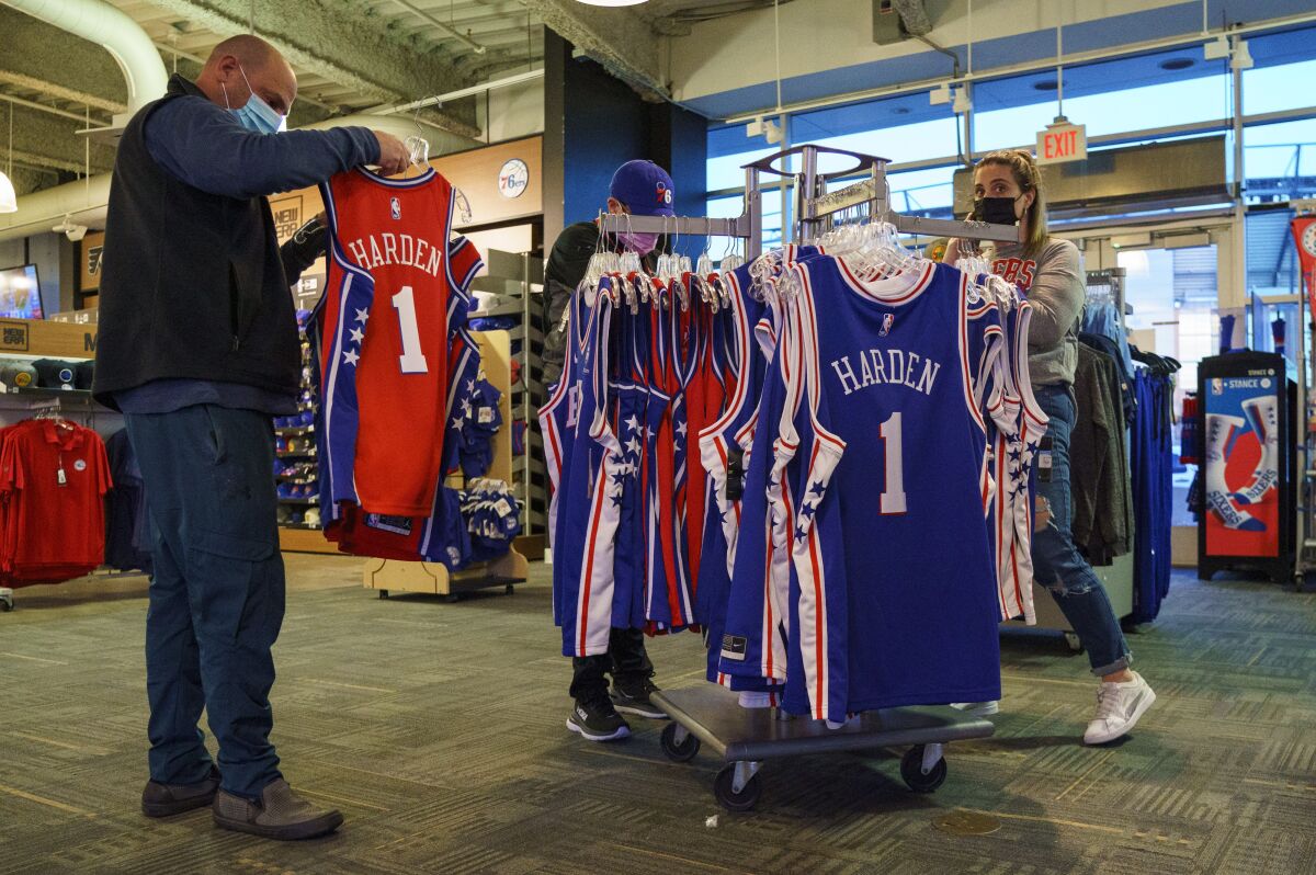 Fans look over the jerseys of newly acquired Philadelphia 76ers' James Harden before the team's NBA basketball game against the Oklahoma City Thunder, Friday, Feb. 11, 2022, in Philadelphia. Harden will not play for the Sixers in games Friday and Saturday night, and he won't play until he's evaluated this weekend by the team's performance staff. The earliest Harden could play for Philly is at home Tuesday against Boston. The Sixers also play Thursday at NBA champion Milwaukee before the All-Star break. (AP Photo/Chris Szagola)