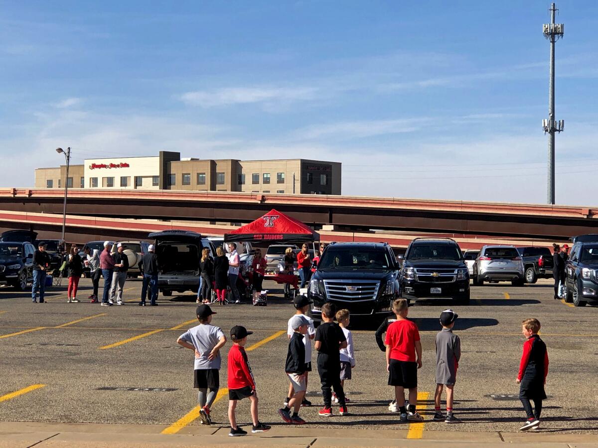 A group of young children stand in a parking lot during the Texas Tech tailgate