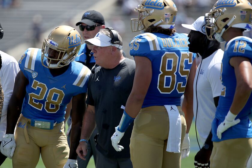 PASADENA, CALIF. - AUG. 28, 2021. Bruins head coach Chip Kelly talks with players during the second quarter.