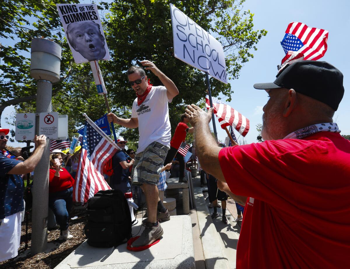 The group that held a rally on Saturday in front of the San Diego County administration building, later marched to a park near the USS Midway Museum. Standing on top of a park table, Andy Loy making his point as the lone voice of opposition, stumped a MAGA ball cap in front of the group.