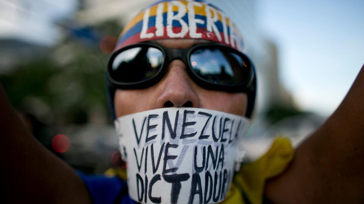 A woman wears a banner over her mouth with a message that reads in Spanish: "Venezuela lives in a dictatorship" during a protest in Caracas, Venezuela, on March 31