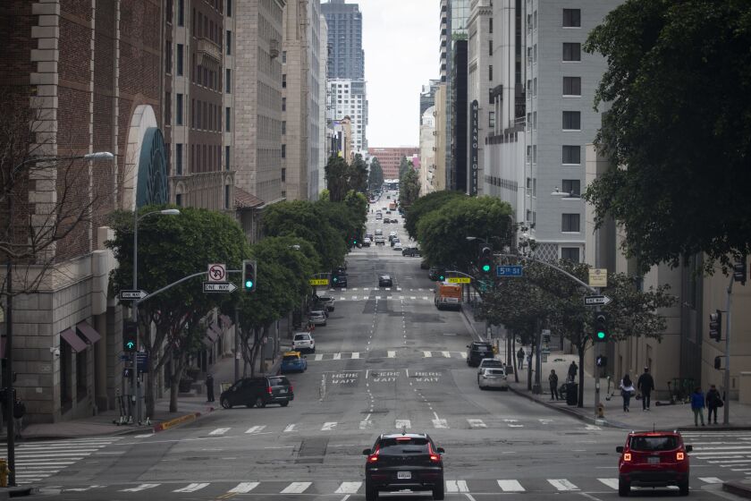 LOS ANGELES, CALIF. - MARCH 15: On a queit Sunday afteroon few cars drive on Grand Ave in Los Angeles, Calif. on Sunday, March 15, 2020. While it is quieter on the streets of Los Angeles, there are still people moving about. (Francine Orr / Los Angeles Times)