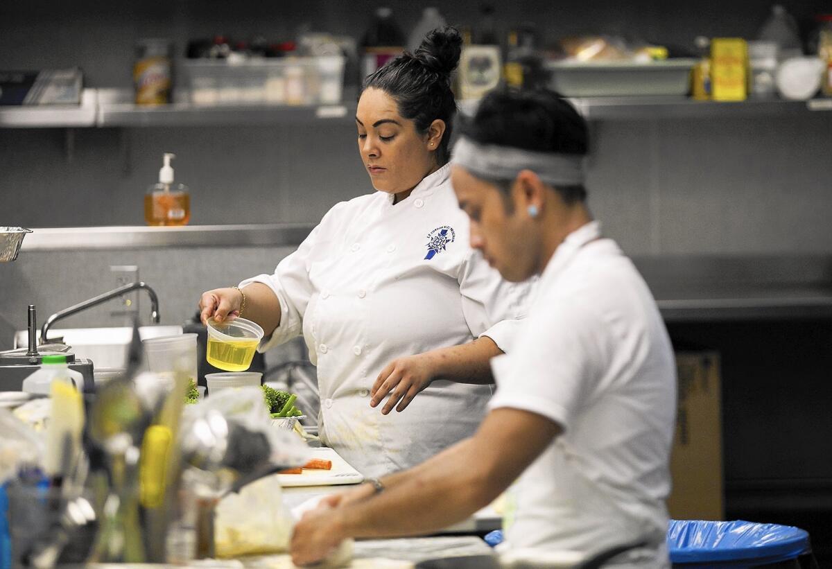 Chefs Denise Brune, left, and Aldrich Mendiola prepare food Tuesday for Dish Republic, a Costa Mesa-based dinner delivery service.