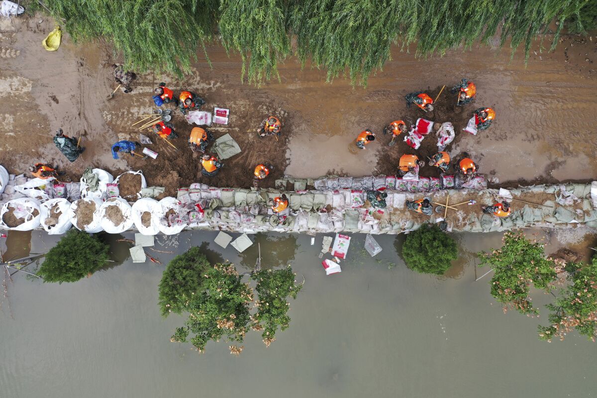 In this photo released by Xinhua News Agency, an aerial photo shows rescuers fortifying a temporary dyke against the flooding at the Lianbo Village in Hejin City, in northern China's Shanxi Province, Sunday, Oct. 10, 2021. (Zhan Yan/Xinhua via AP)