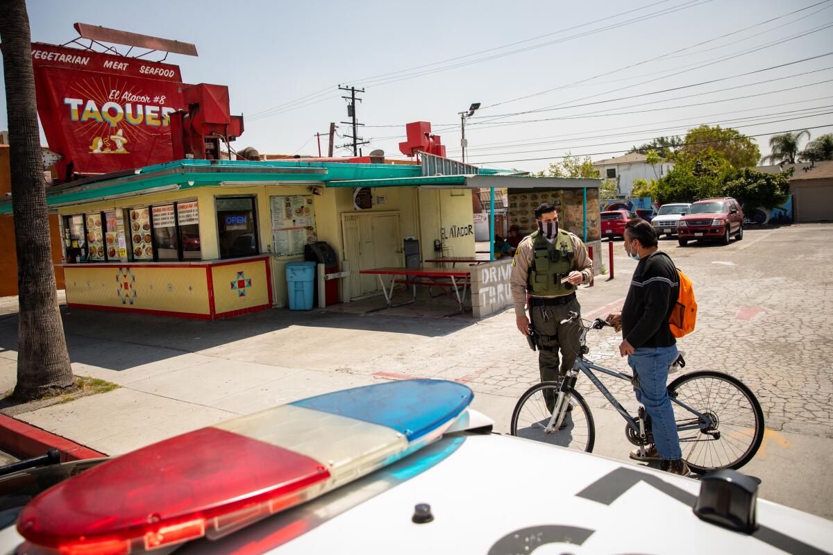 A  deputy talks with a man riding his bike on the sidewalk along Whittier Boulevard