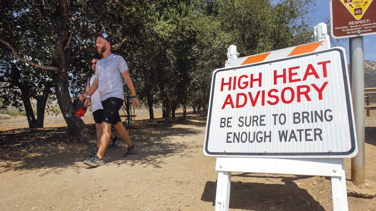 Chris Capeau, right, and Ryan Williams walk toward the parking lot after hiking the Iron Mountain Trail in Poway on Thursday. Iron Mountain and other popular trails will be closed to the public the next few days because of predicted extreme heat.
