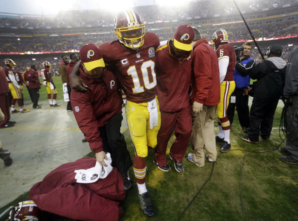 Washington Redskins quarterback Robert Griffin III is helped off the field after an injury during the second half of a game in December against the Baltimore Ravens in Landover, Md. The league has disavowed any effort to help promote the new health insurance subsidies created by the 2010 federal healthcare law, a.k.a. Obamacare.