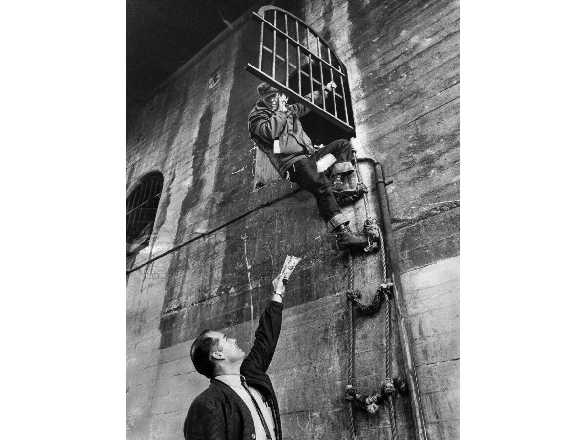 Dec. 23, 1969: Preston Tingle comes down rope ladder from his pad under 7th Street Bridge to accept his $25 reward from freight terminal manager Jim Hammett.