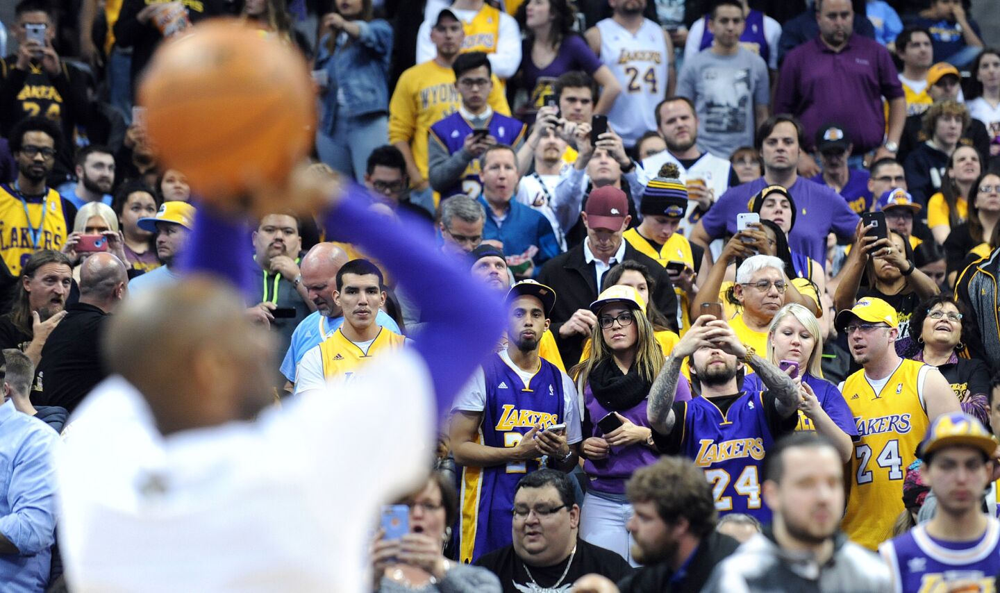 Lakers fans watch Kobe Bryant warm up before a game againstthe Nuggets in Denver on March 2, 2016.
