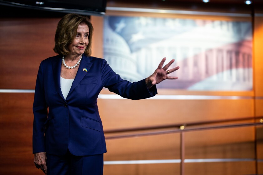 Nancy Pelosi waves as she leaves a press conference