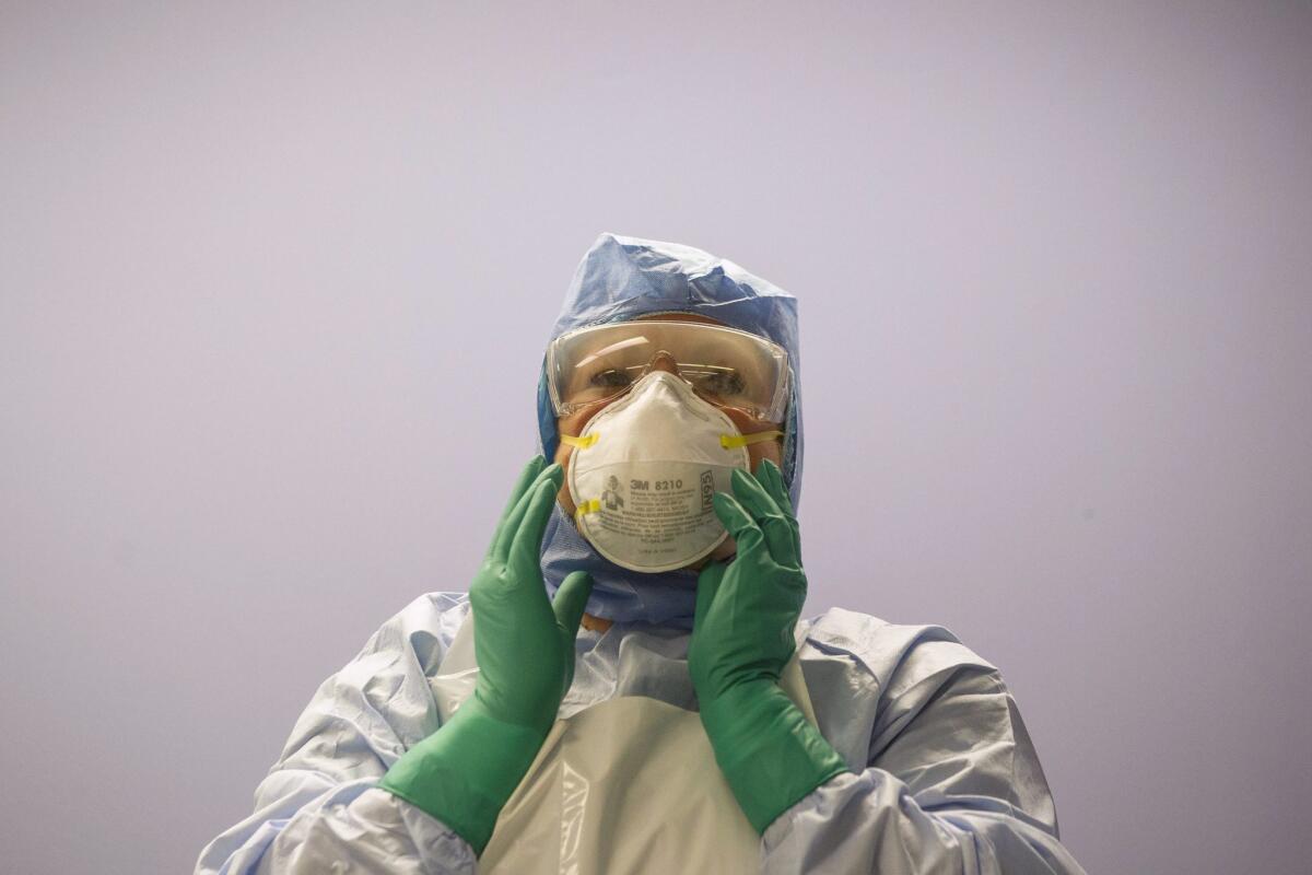 A healthcare worker adjusts her mask during a demonstration of personal protection equipment at Toronto Western Hospital in October. Canada is limiting travel from the countries hardest hit by Ebola.