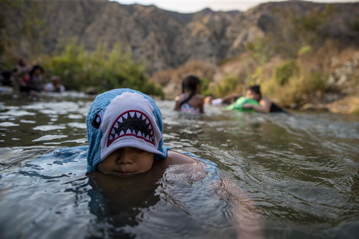 Matthew Giron, 8, frolics with friends and family near a drainage pipe along the San Gabriel River.
