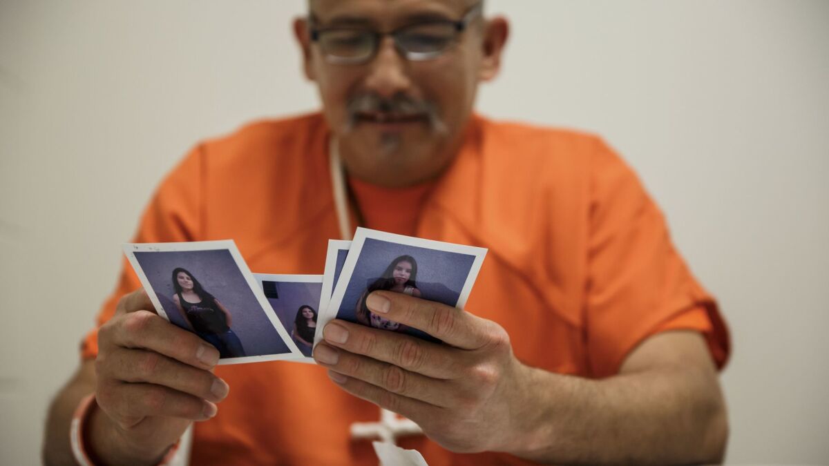 Romulo Avelica looks through family photos at the ICE detention facility in Adelanto, Calif.
