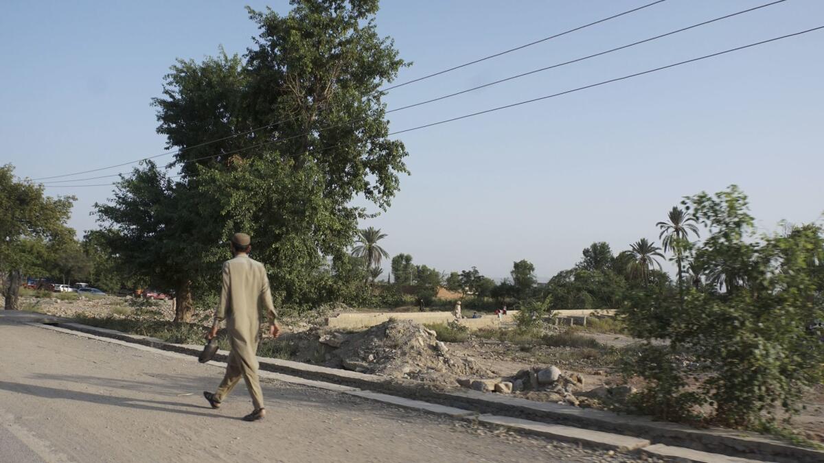 A man walks past destroyed homes near Mir Ali.