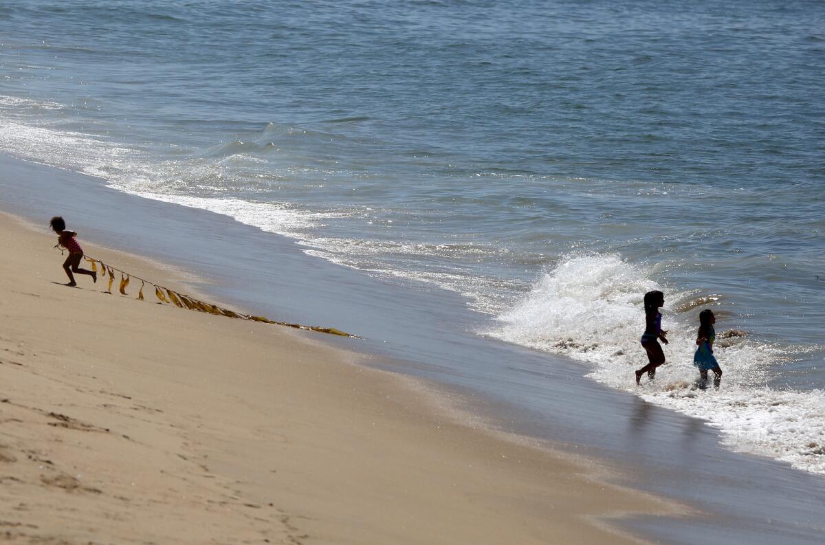 Kids play on the beach next to the Balboa Pier in Newport Beach on Wednesday.