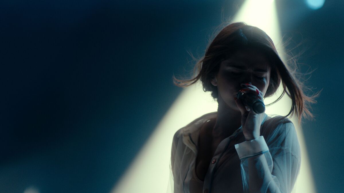 A woman with her face in shadow sings onstage in "Selena Gomez: My Mind & Me."