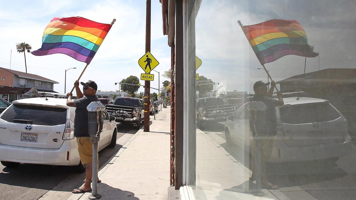 Jay Corona waives the rainbow flag to passing traffic in front of the Main Street Bar and Cabaret on South Coast Highway in Laguna Beach in 2015 in honor of the landmark Supreme Court decision in favor of same-sex marriage.