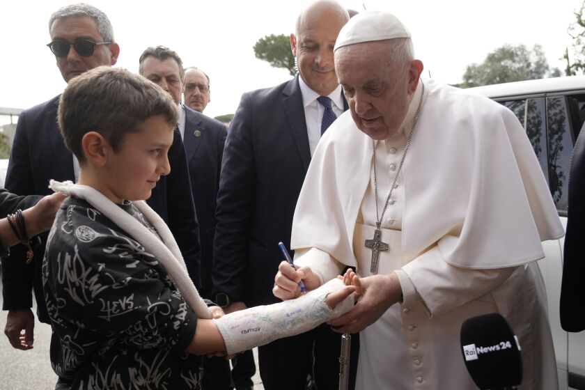 Pope Francis autographs the plaster cast of a child as he leaves the Agostino Gemelli University Hospital in Rome, Saturday, April 1, 2023 after receiving treatment for a bronchitis, The Vatican said. Francis was hospitalized on Wednesday after his public general audience in St. Peter's Square at The Vatican. (AP Photo/Gregorio Borgia)