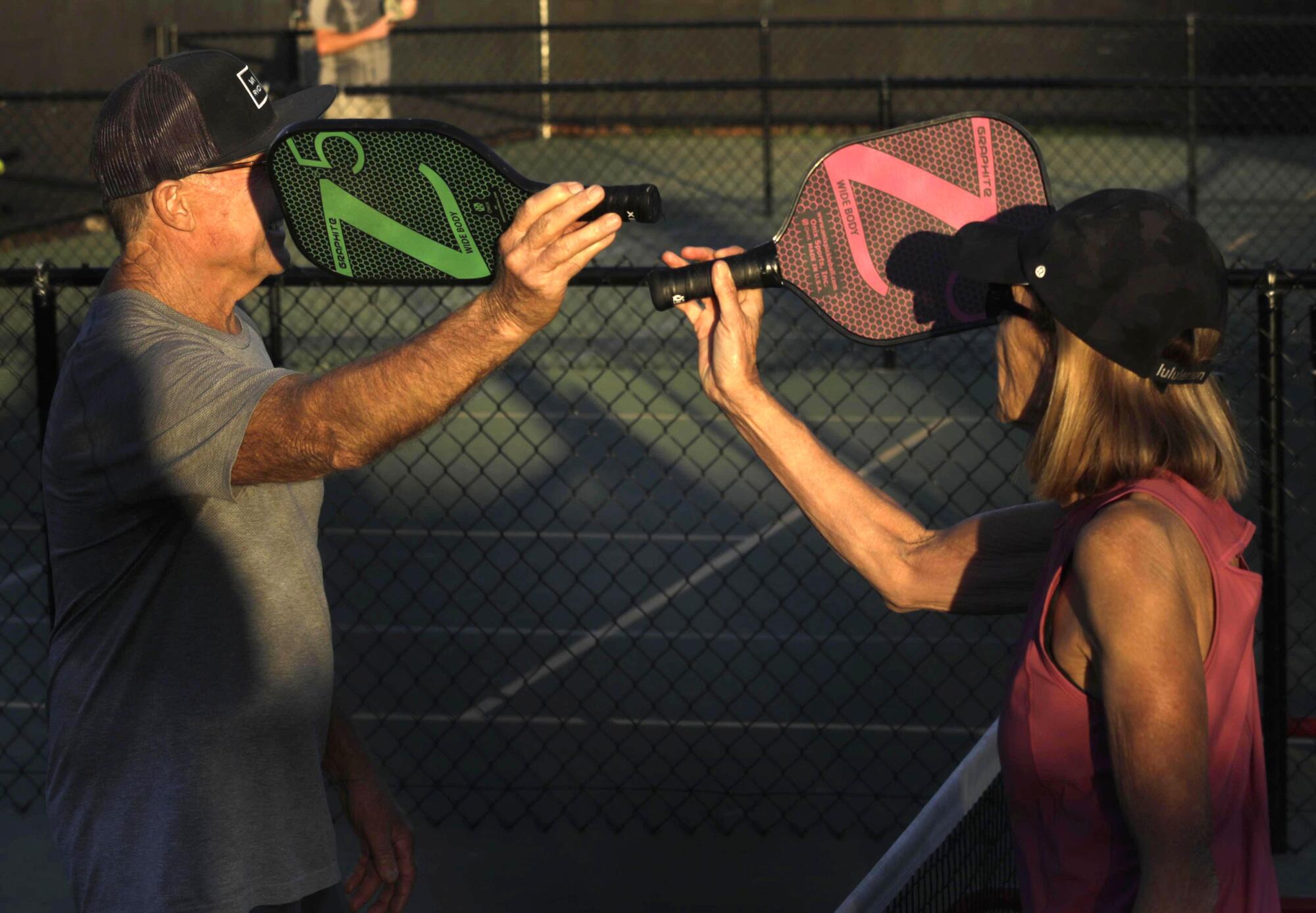 Steve Lough and his wife, Judy, tap paddles at the end of a pickleball game